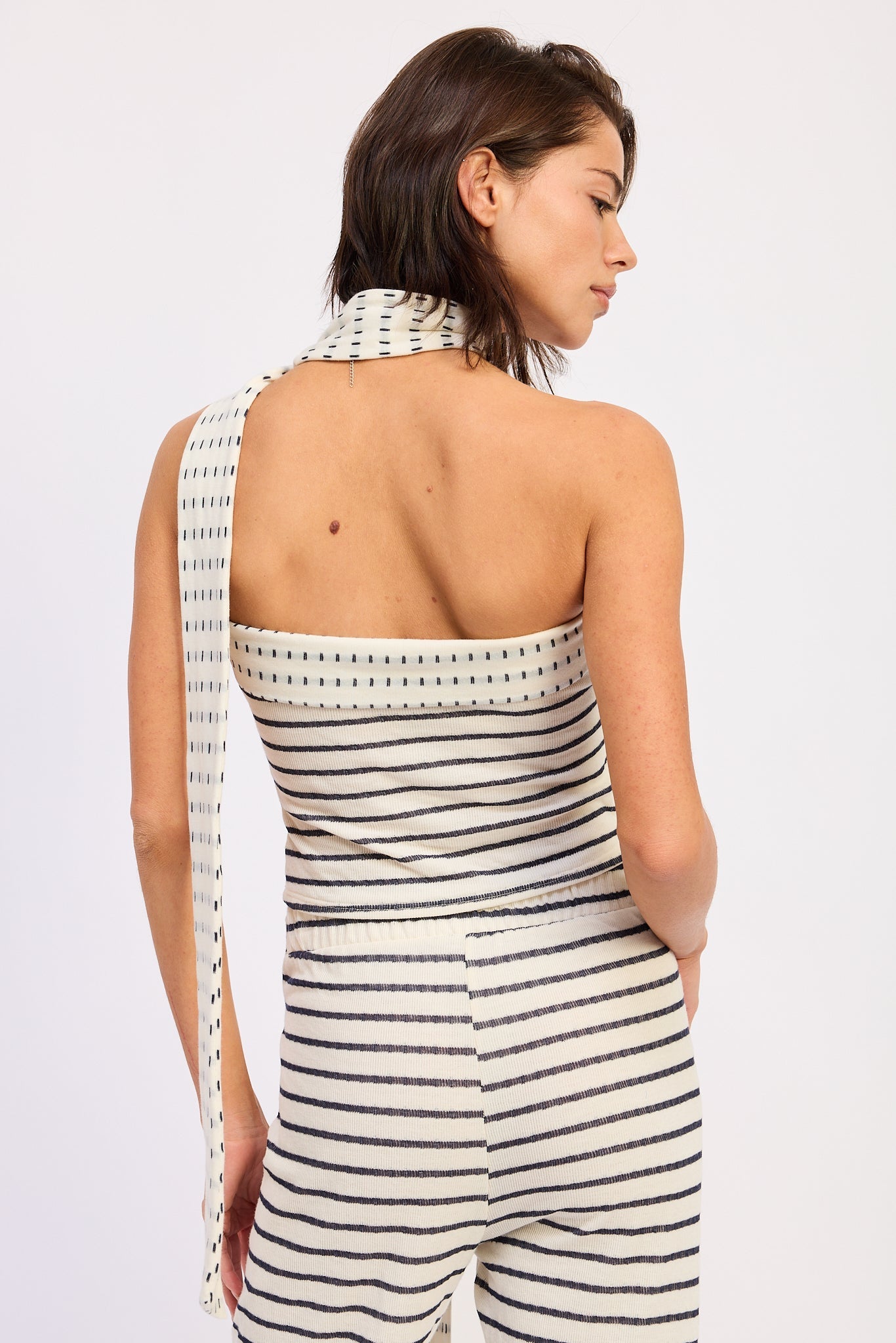 Woman wearing an ivory striped bandeau top with a scarf on a white  back view