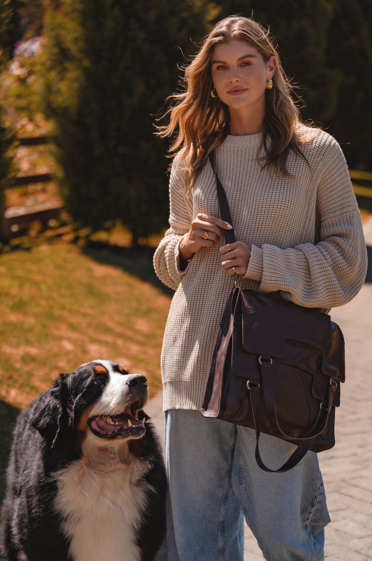 Woman walking a dog on a path with a brown bag