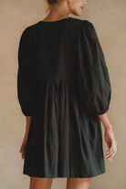 Black dress with balloon sleeves on a neutral background