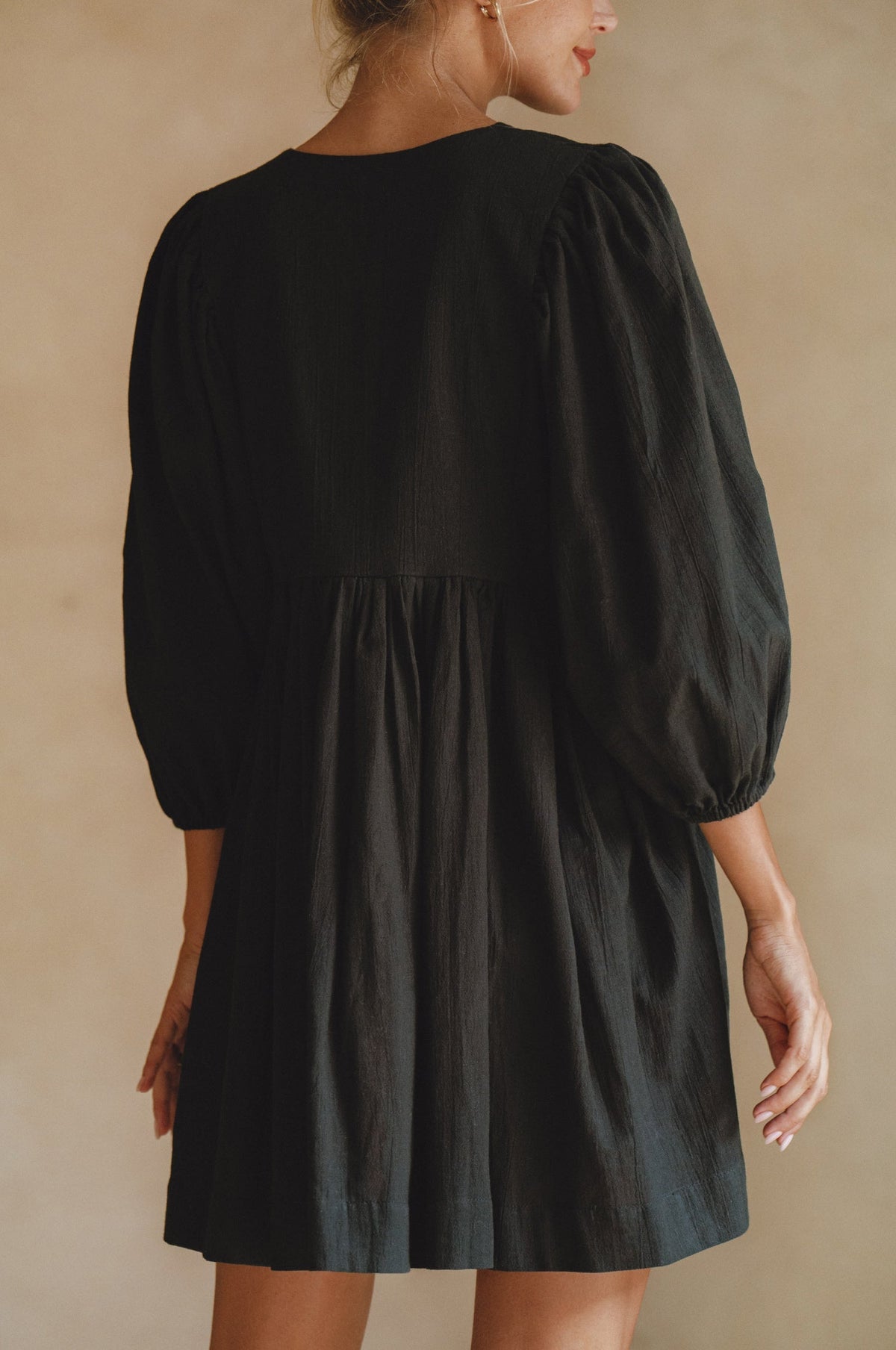 Black dress with balloon sleeves on a neutral background