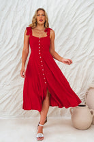 Woman wearing a red square neckline and button-down fit-and-flare midi dress with adjustable tie-up straps against a neutral background, front view