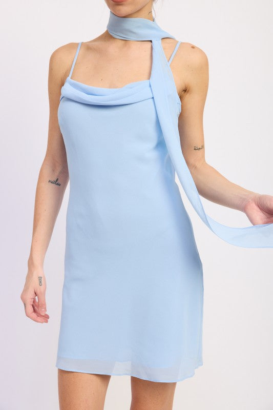 Woman wearing a light blue mini dress with cowl neckline and scarf on a white background front view