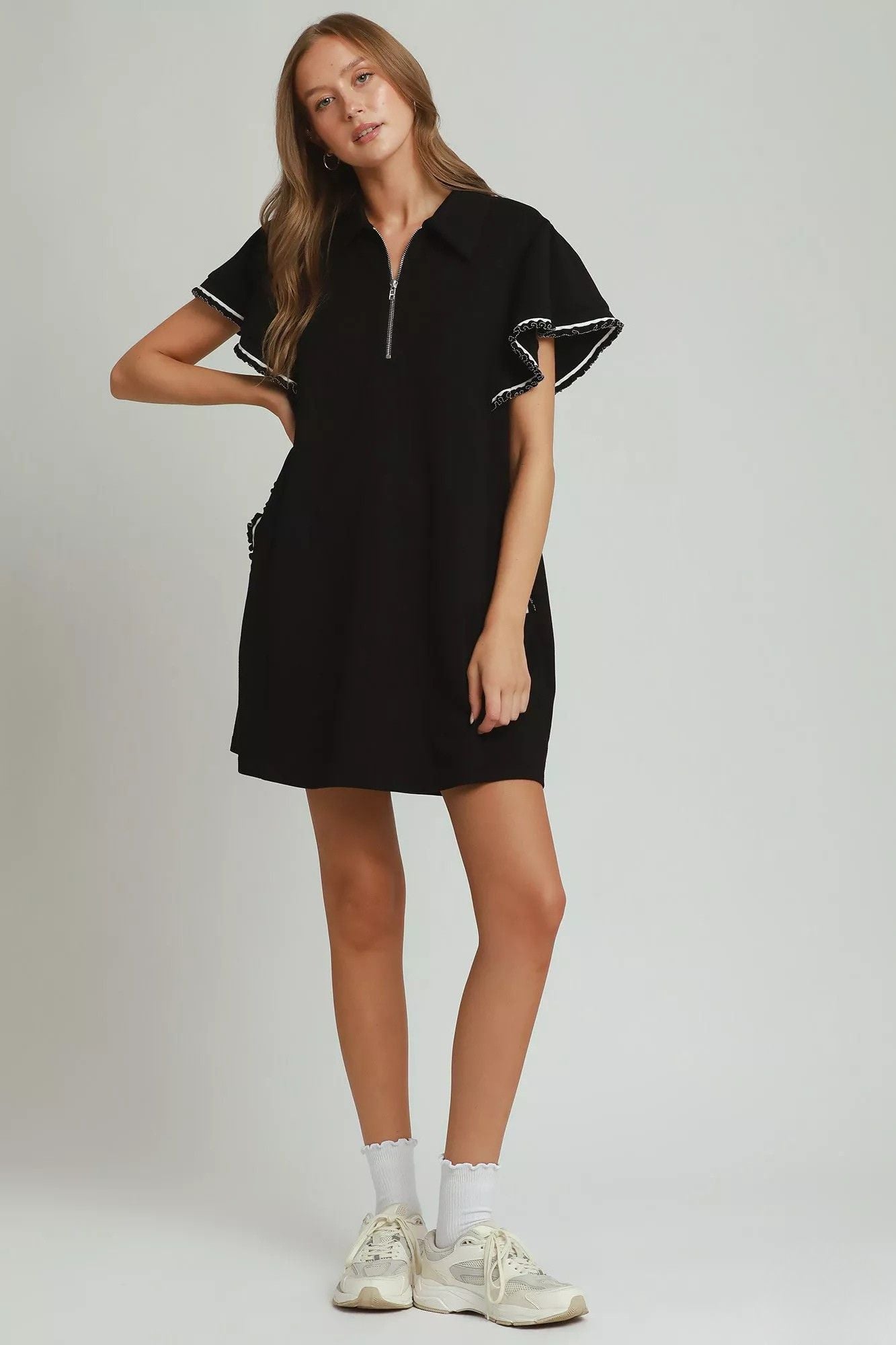 Full length view of black mini dress styled with white sneakers and socks, AVAH