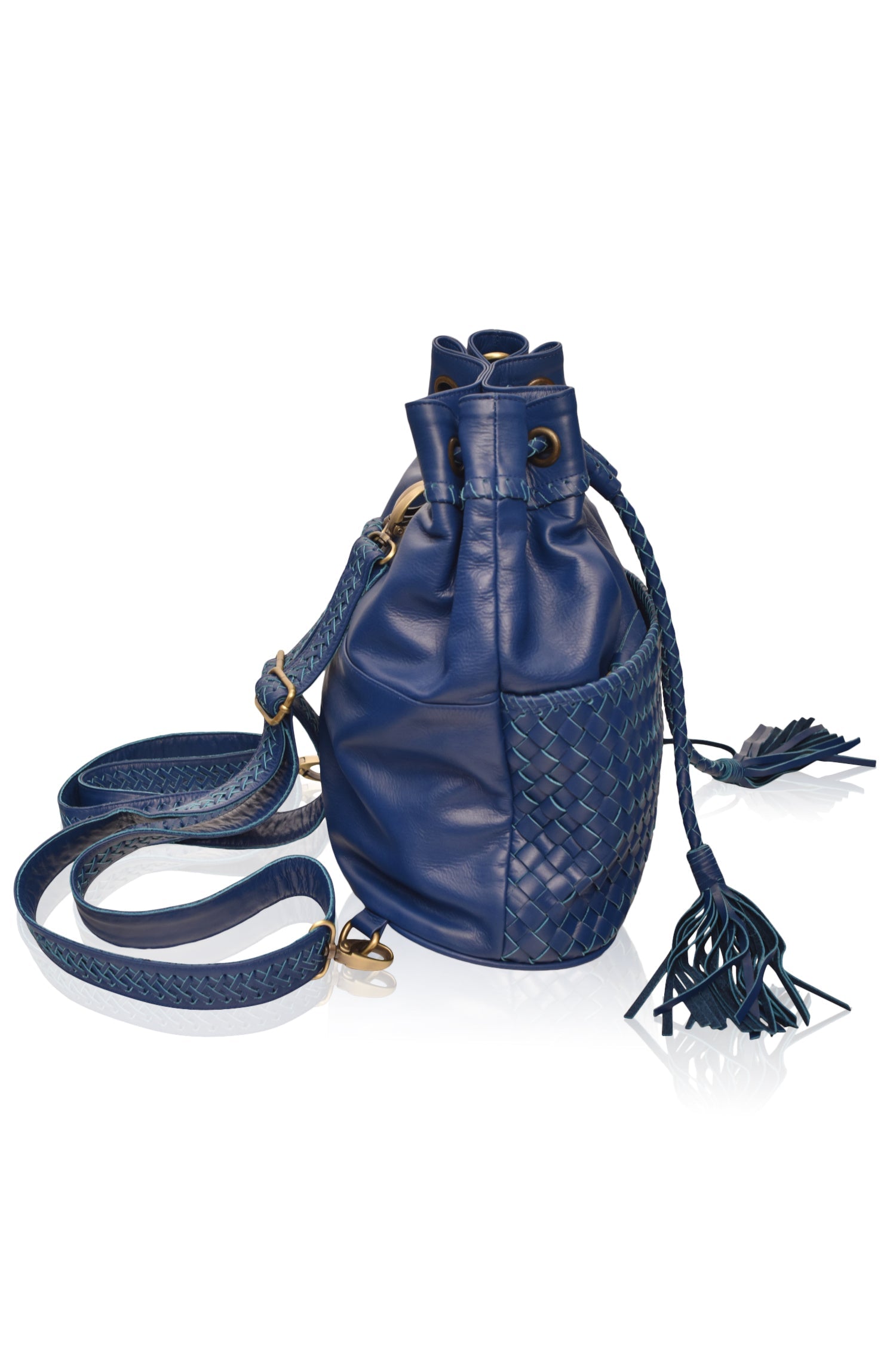 Blue leather woven backpack/handbag with braded drawstring opening, woven detailed pocket on the front and braided adjustable straps with brass hardware on the front on white background, side view