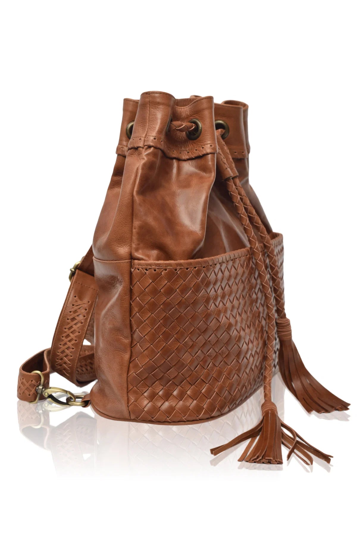 Camel leather woven backpack/handbag with braded drawstring opening and braided adjustable straps with brass hardware on the front on white background, side view