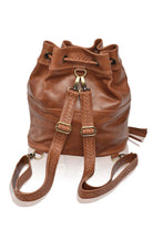 Camel leather woven backpack/handbag with braded drawstring opening and braided adjustable straps with brass hardware on the front on white background, back view