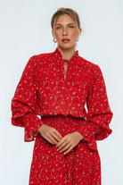Woman wearing a red dress with a subtle pattern on a light gray background