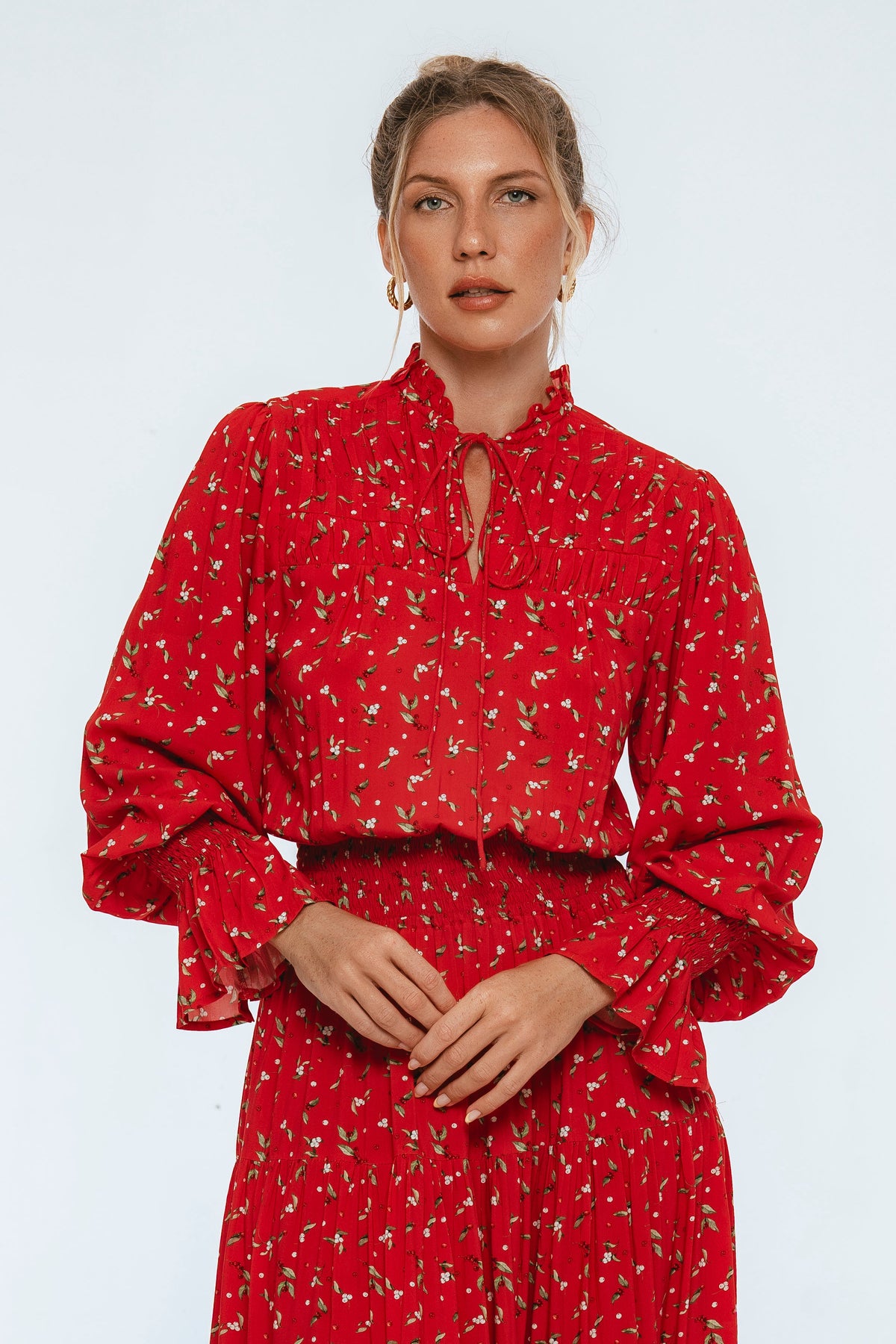Woman wearing a red dress with a subtle pattern on a light gray background