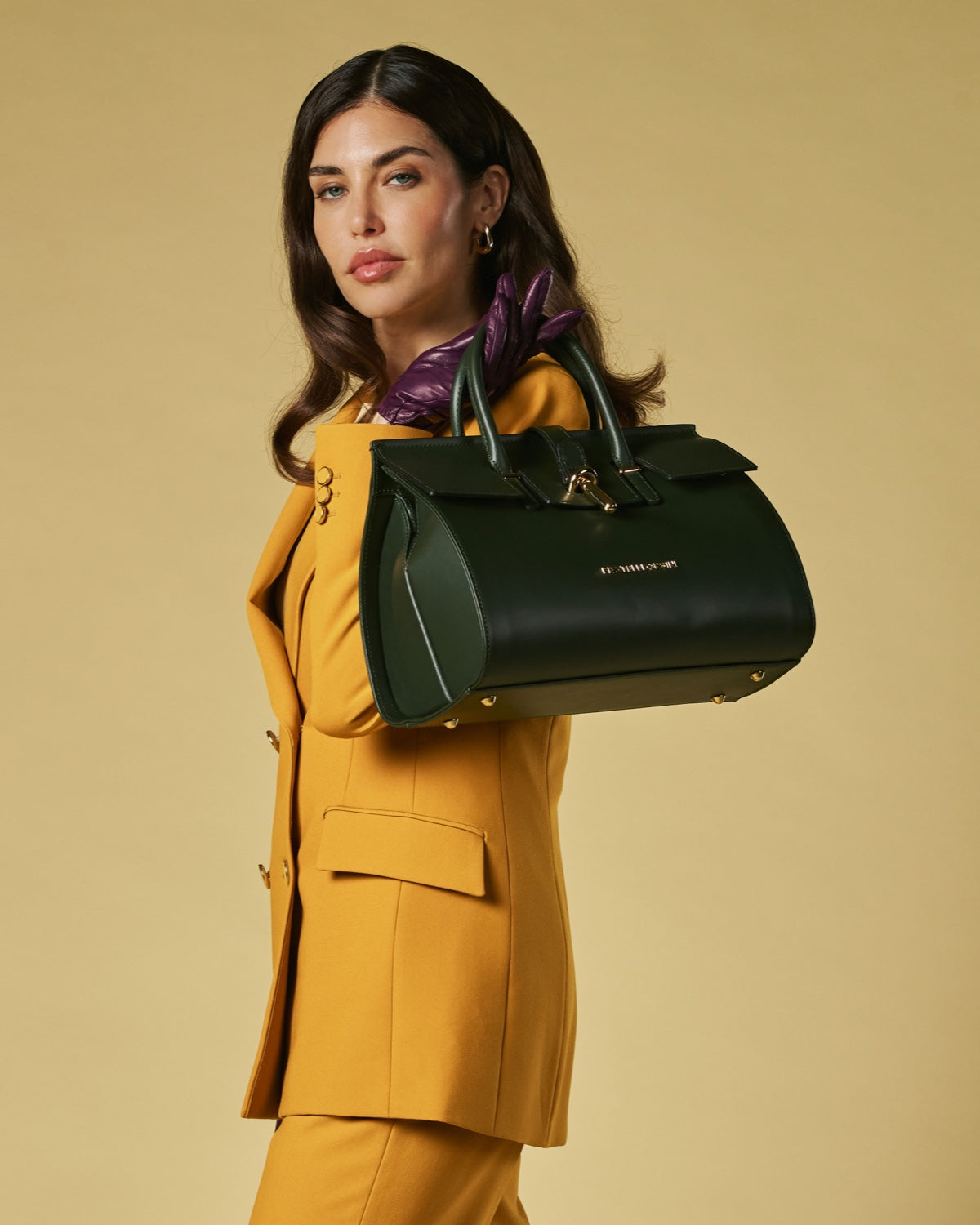 Woman holding a green leather handbag against a beige background