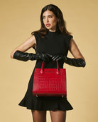 Woman holding a red handbag against a beige background
