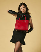 Woman holding a red handbag against a beige background