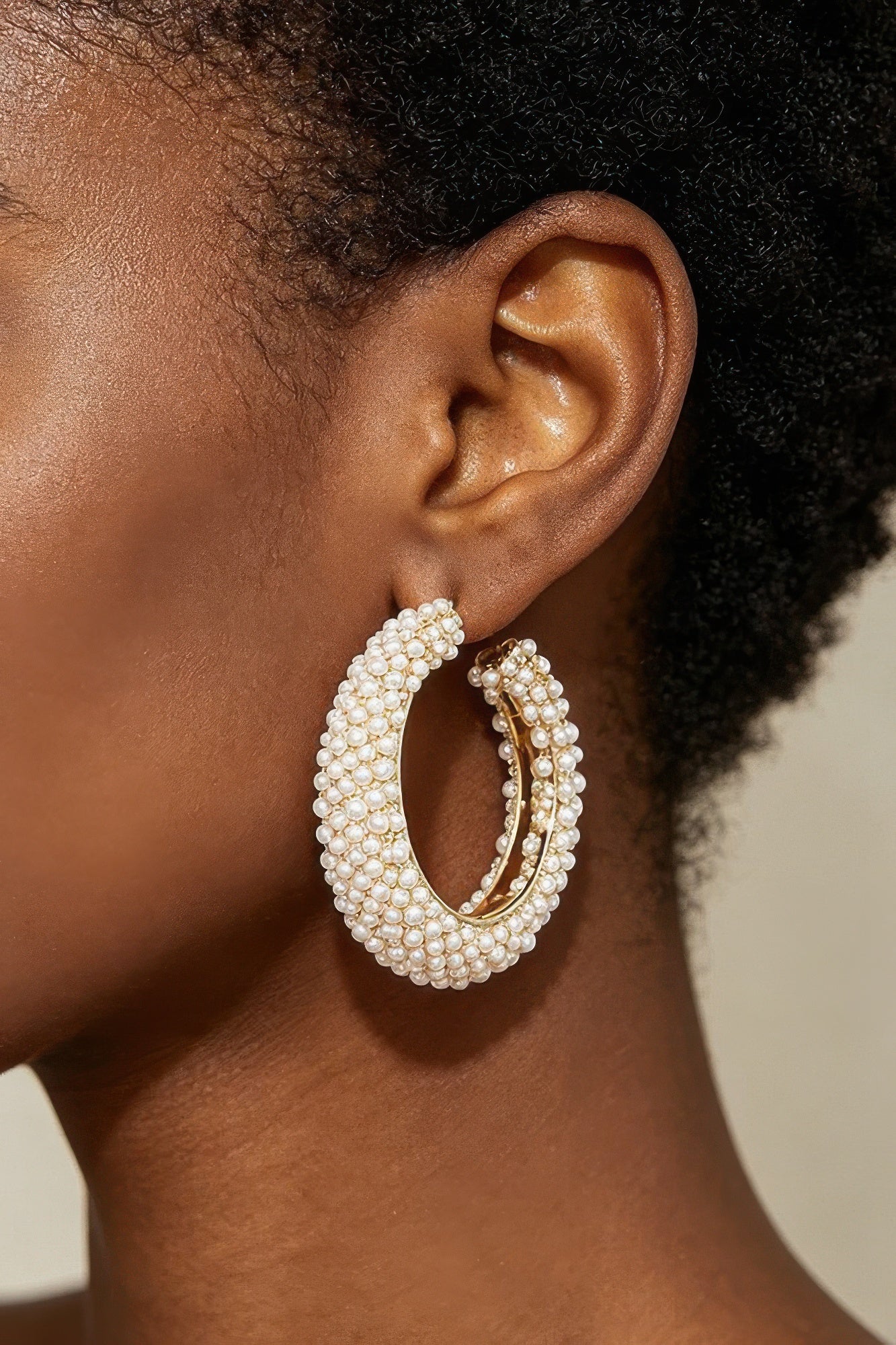 Pearl Reverie Statement Hoop Earrings with clustered white pearls and gold tone accents worn on the ear.