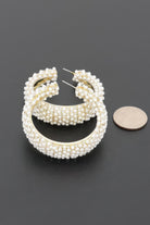 Pearl Reverie pearl encrusted hoop earrings shown with coin for size reference.