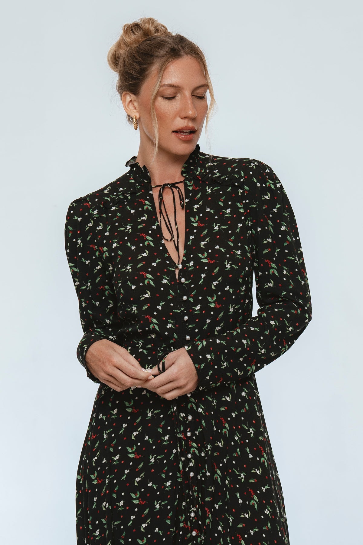 Woman wearing a black floral dress against a light blue background