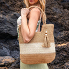 Two-tone straw tote adorned with a wooden bead and straw tassel