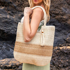 Two-tone straw tote adorned with a wooden bead and straw tassel