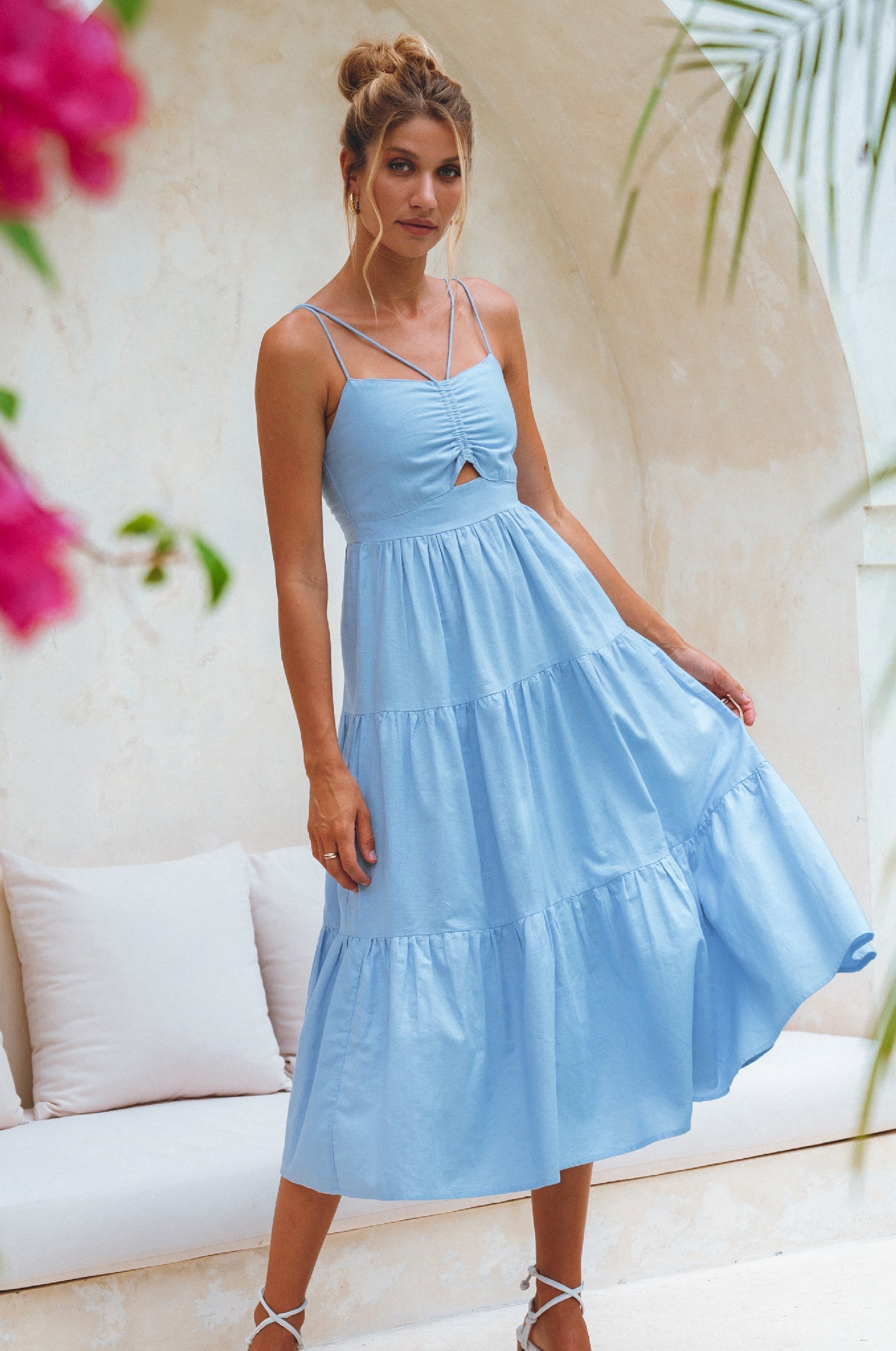 Woman wearing a light blue dress with a floral and indoor setting background