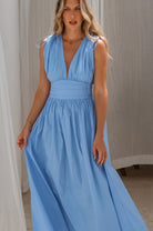 Woman wearing a blue maxi dress against a neutral background