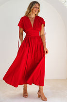 Woman wearing a red maxi dress with deep v-neckline against a white background