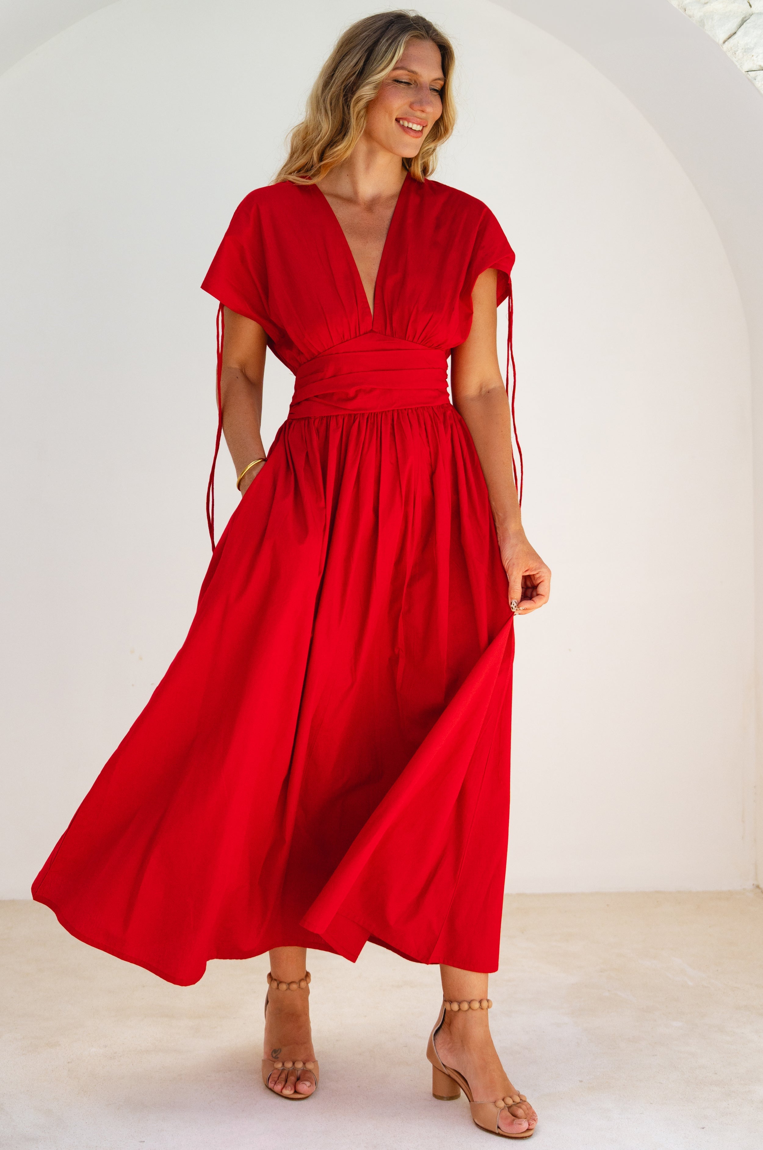 Woman wearing a red maxi dress with deep v-neckline against a white background