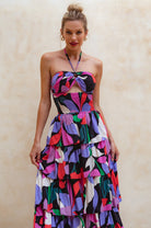 Woman wearing a colorful strapless dress against a beige background