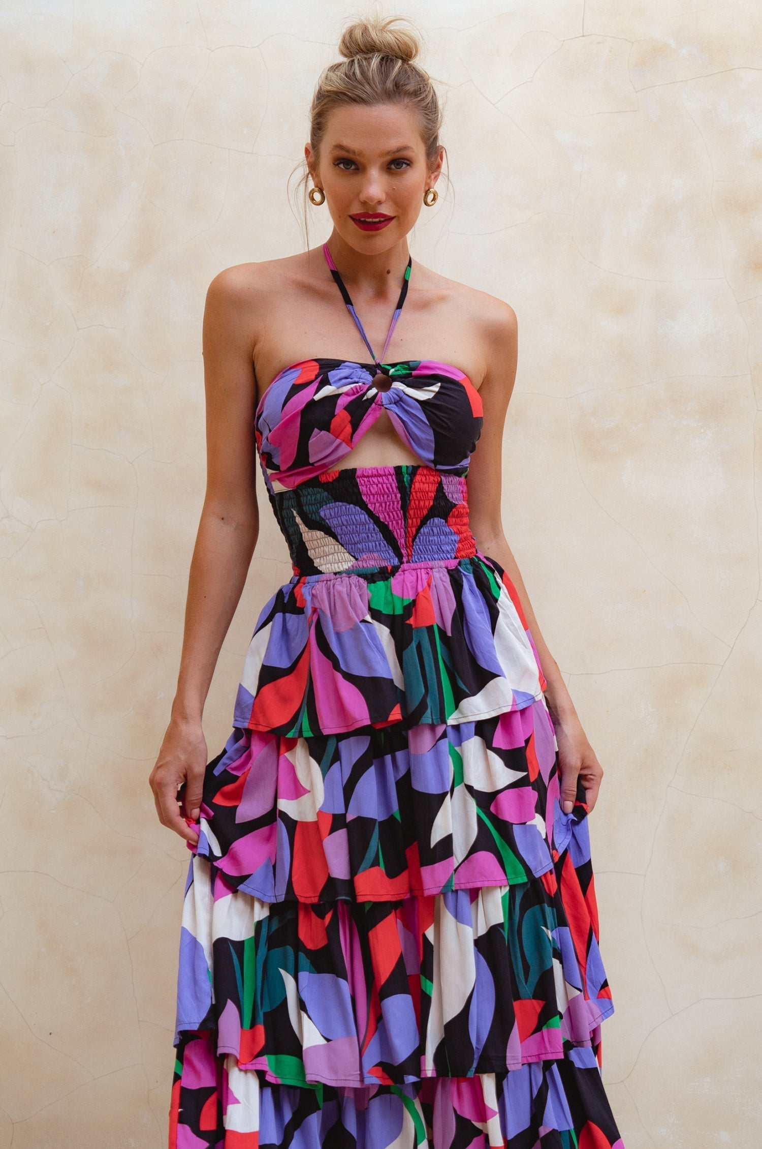 Woman wearing a colorful strapless dress against a beige background