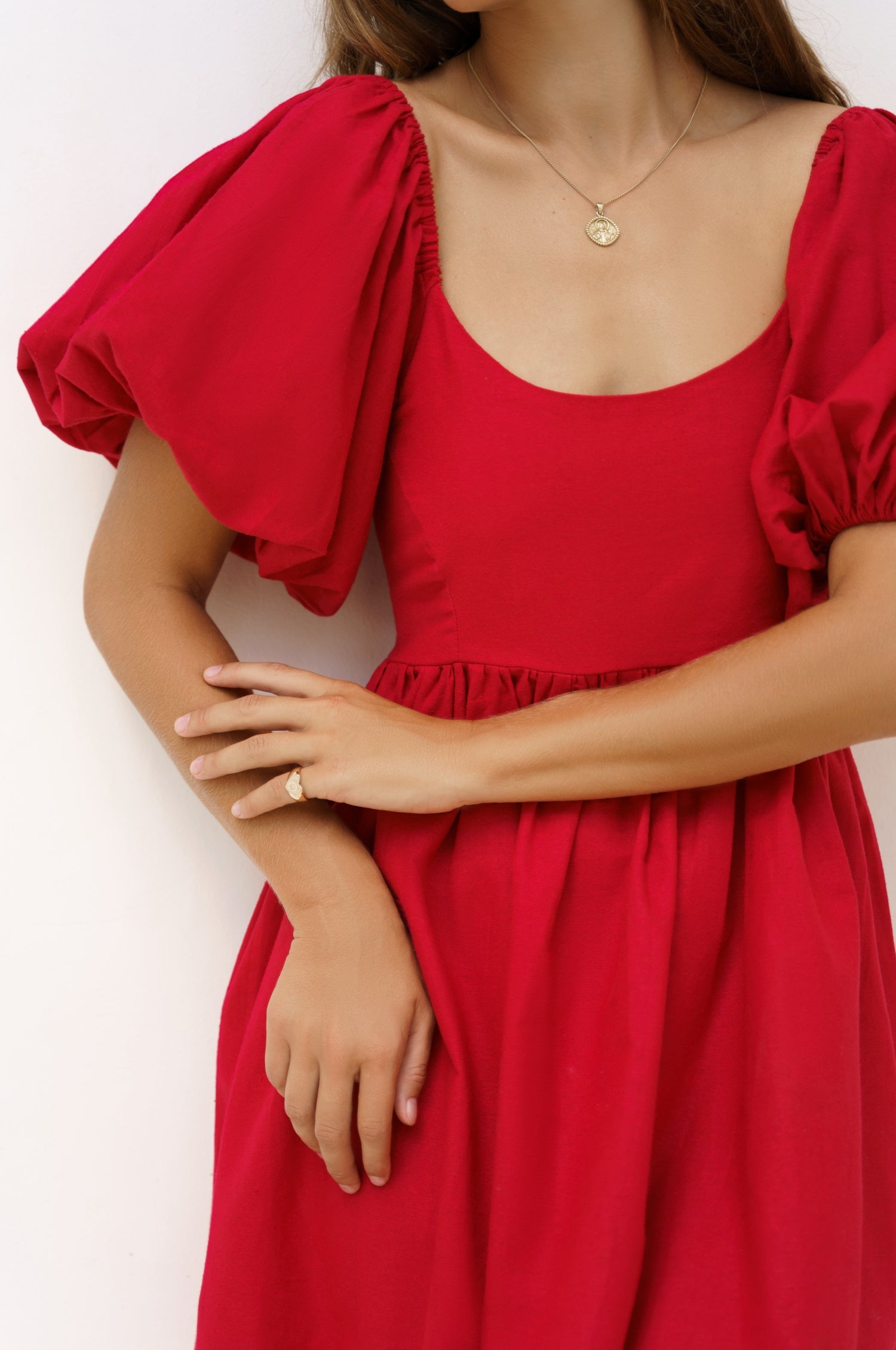 Red dress with puff sleeves worn by a person on a white background