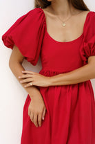 Red dress with puff sleeves worn by a person on a white background