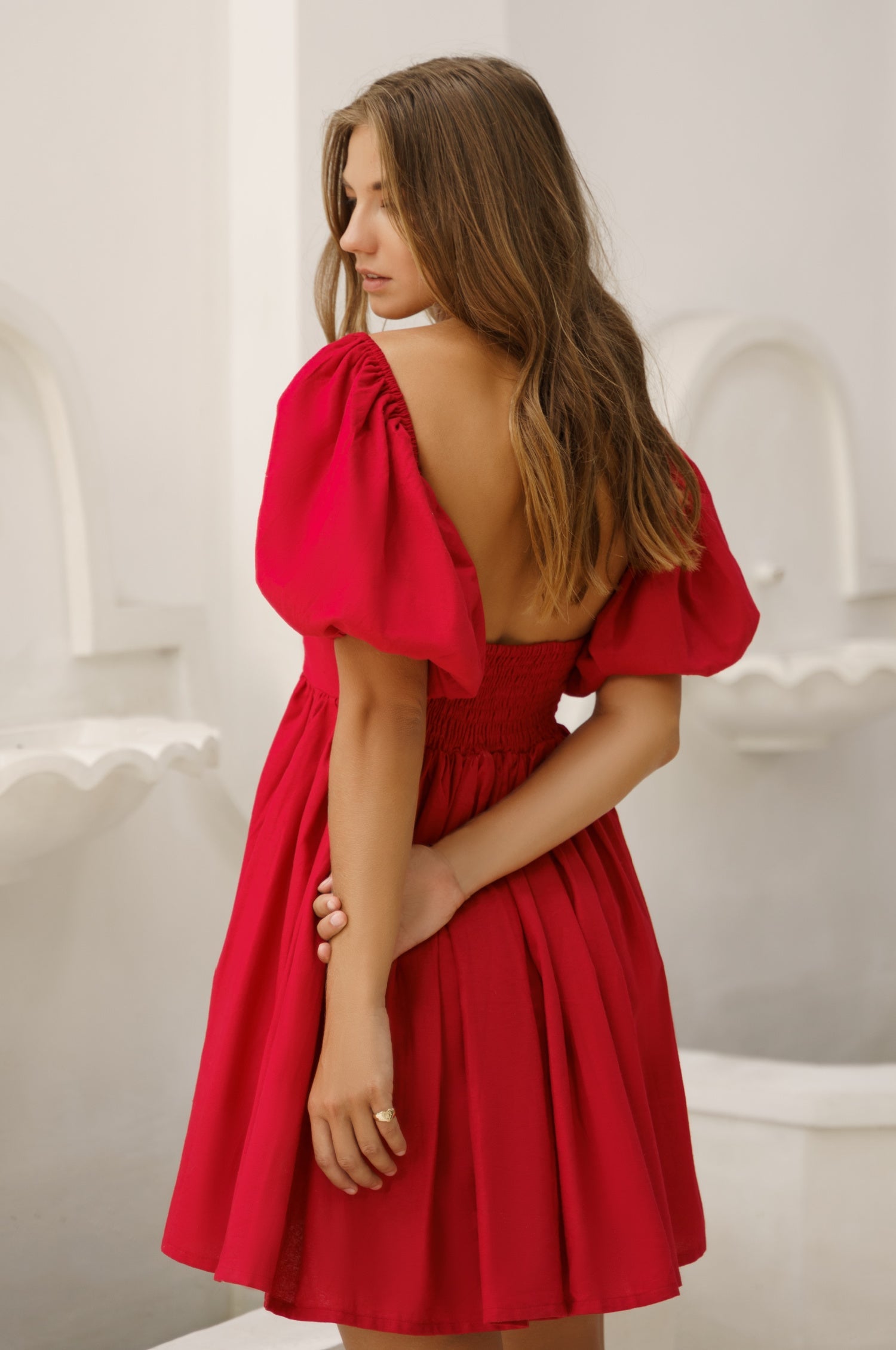 Woman wearing a red dress with open back in an indoor setting, back view. 