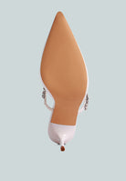 White mid-heeled shoe with a decorative diamante strap across the top on a light blue background, bottom view