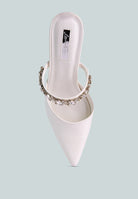 White mid-heeled shoe with a decorative diamante strap across the top on a light blue background, top view