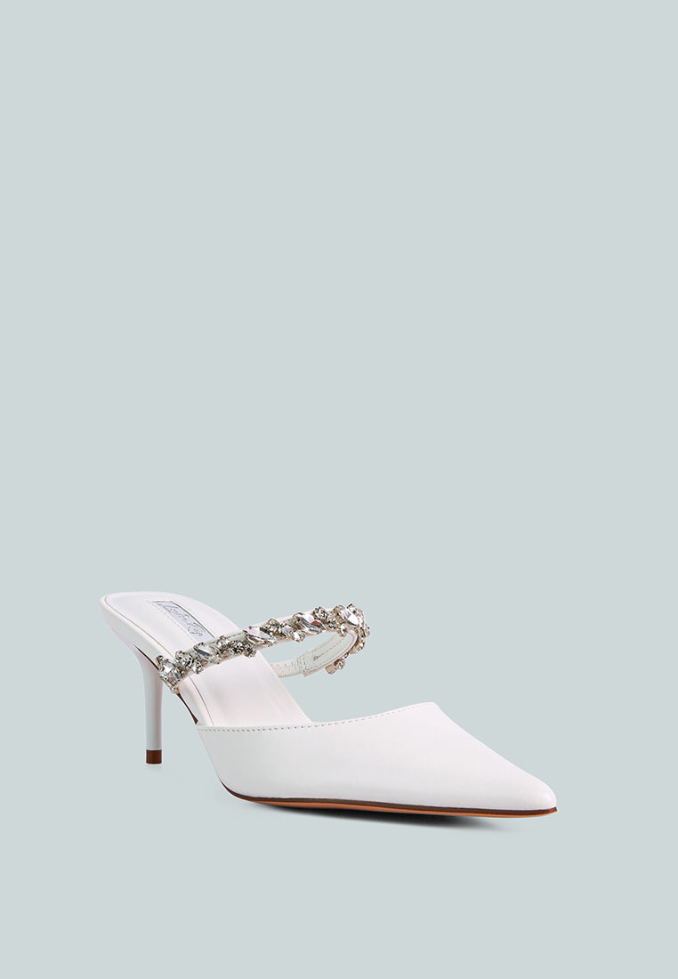 White mid-heeled shoe with a decorative diamante strap across the top on a light blue background, front angle view