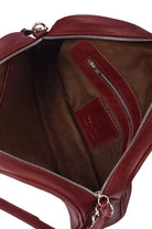Close-up of the brown suede lining of a maroon leather bag with a visible brand logo on a white background