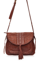 Brown worn leather woven handbag with a tassel and long adjustable strap on a white background