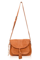 Tan woven leather crossbody bag with a tassel and a long adjustable strap on a white background