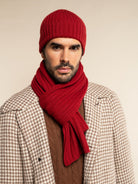 Man wearing a red cashmere knit beanie and scarf against a beige background