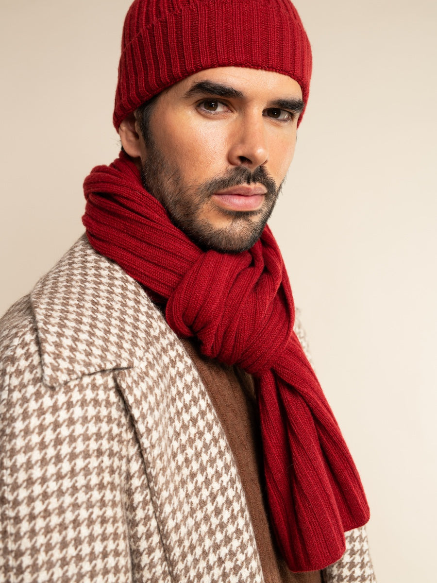 Man wearing a red knit hat and scarf against a beige background