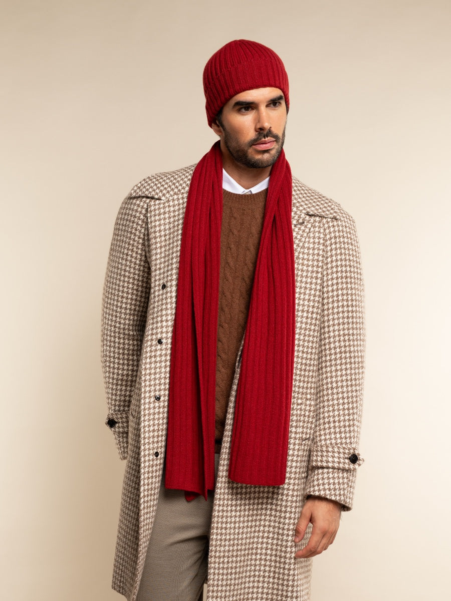 Man wearing a red beanie, scarf, and checkered coat on a beige background