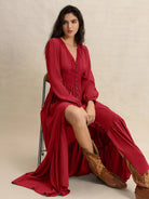 Scarlett Grace Button Front Maxi Dress in deep scarlet red — model sitting, button-front bodice unbuttoned low to reveal a leg-baring opening.