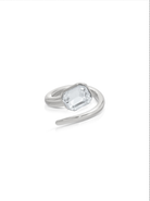 Silver-tone open wrap ring with clear rectangular crystal on white background.