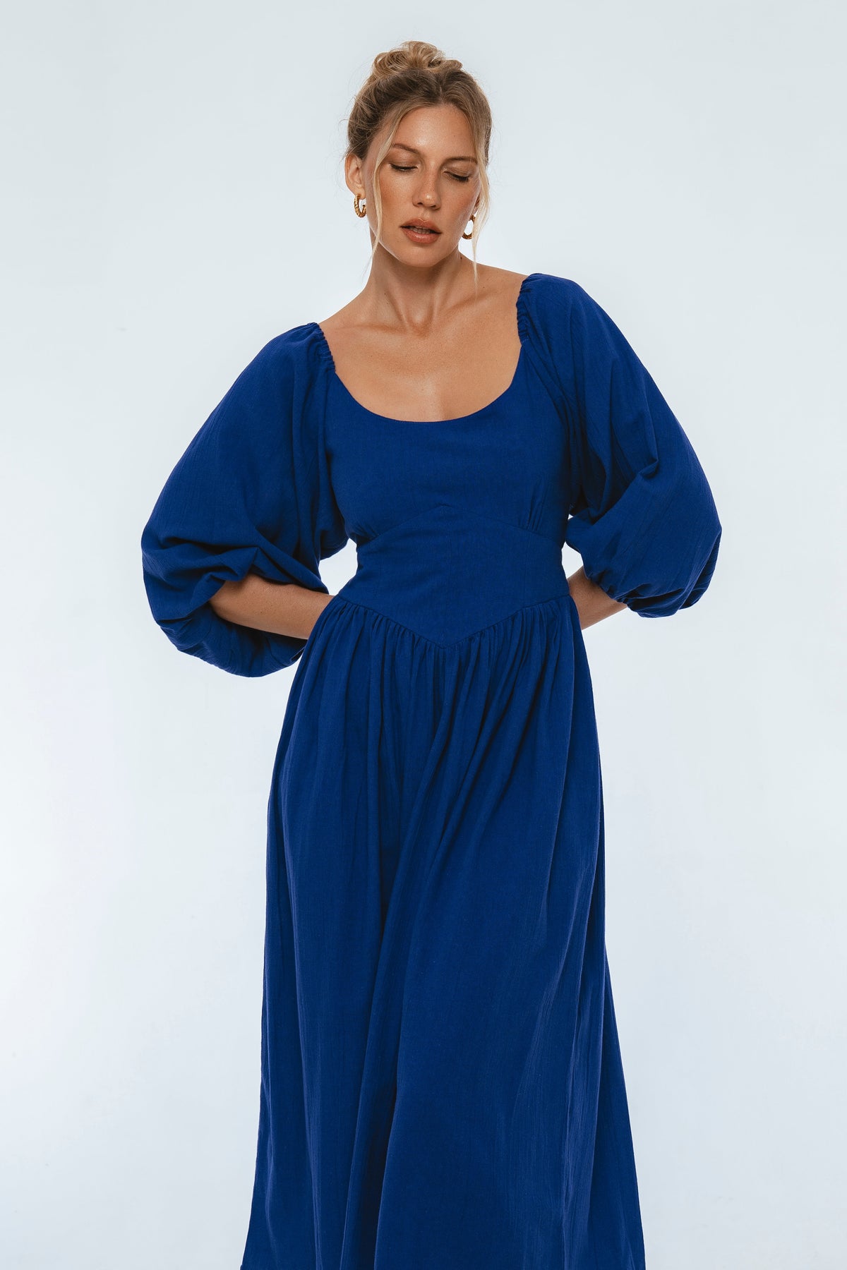 Woman wearing a blue dress with puffed sleeves against a white background