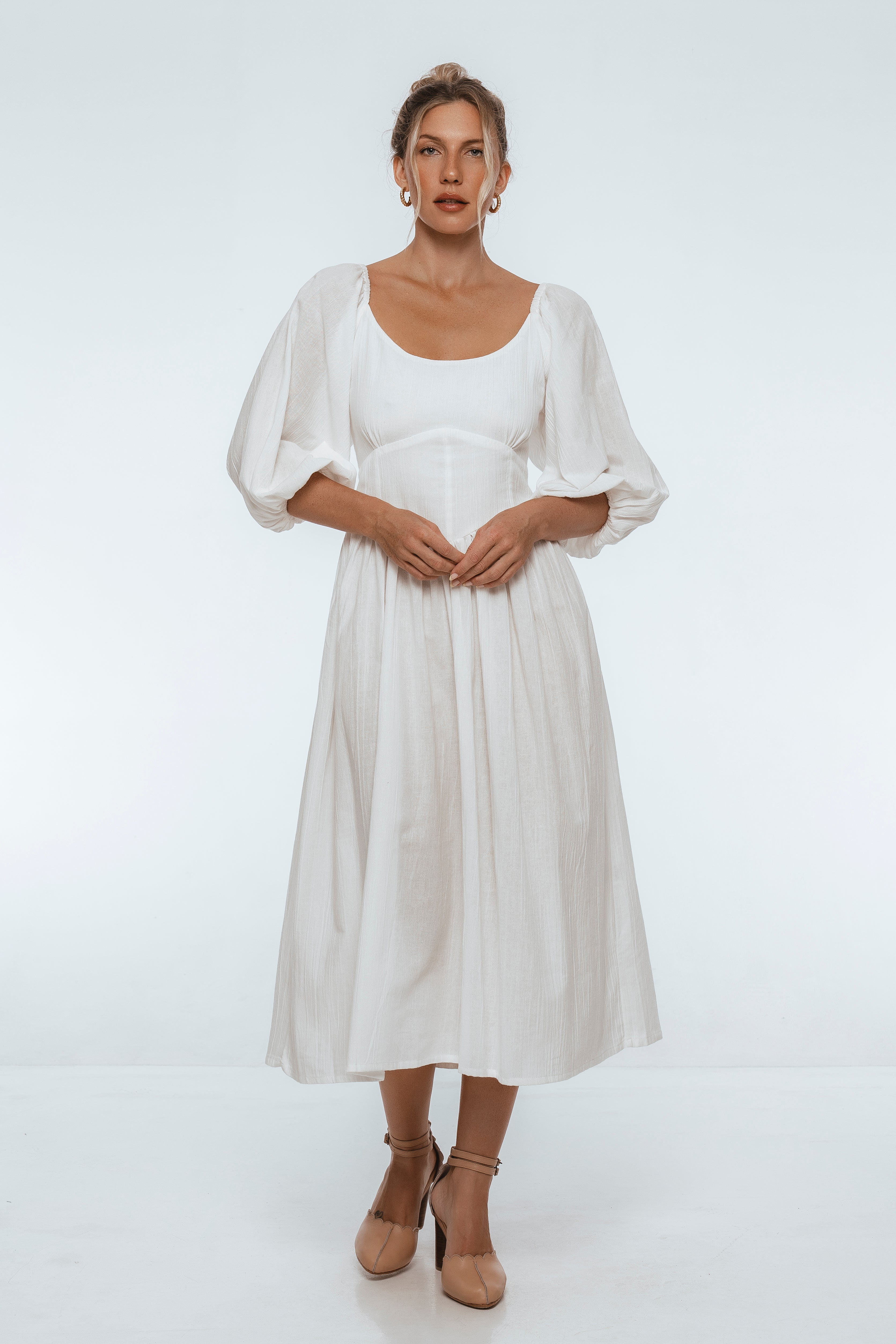 Woman wearing a white midi dress with puff sleeves on a white background