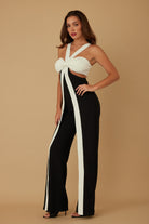 Side angle of model in halter jumpsuit showing front bow and leg panels
