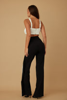 Rear side angle of model showing fit of wide-leg pants and back design
