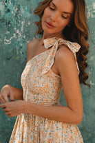 Woman wearing a floral dress against a textured teal wall