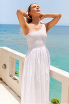 Woman wearing white one-shoulder dress with a fitted bodice, smocked at the bust, midi length, 3/4 view