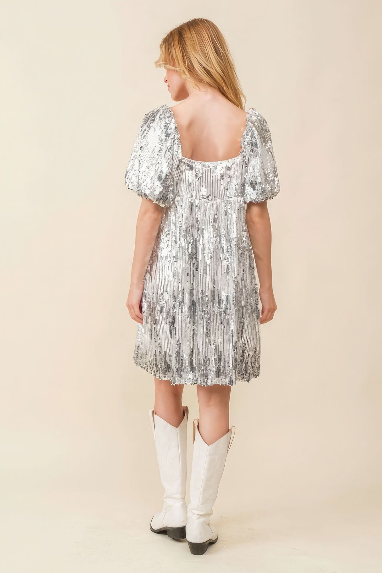 Back full view of silver sequin mini dress with square back and puff sleeves.