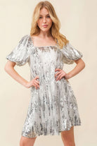 Close-up front view of square neckline and puff sleeves on silver sequin mini dress.
