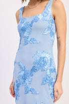 Woman wearing a light blue floral embroidered mesh mini dress with appliqué detail and open back on a white background closeup