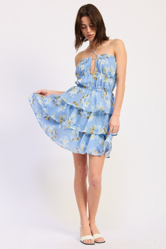 Woman wearing a blue floral ruffle tiered mini dress against a white background front view